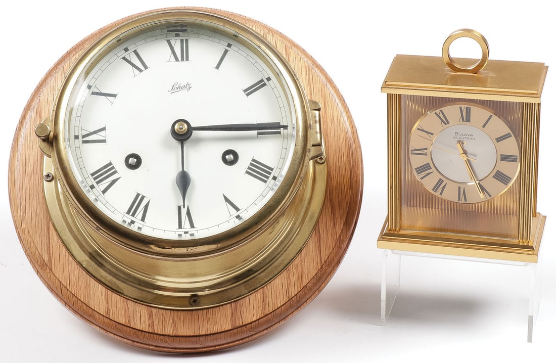 A PR OF CLOCKS: A PR OF CLOCKS. Including a Schatz ships clock mounted on wooden base, diameter of dial 6.25 inches. Together with a Bulova Accutron desk clock, height 5.75 inches.SHIPPING NOTICE:Except for large,