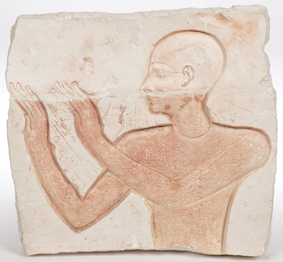 AN EGYPTIAN CARVED LIMESTONE FRAGMENT: AN EGYPTIAN CARVED LIMESTONE FRAGMENT. Depicting a half-length male figure with traces of polychroming in the ancient style. 10.5 inches x 11.5 inches, thickness approximately 2 inches. Provenance: Th