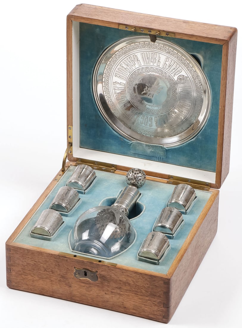 SILVER & GLASS CASED VODKA SET GRACHEV: SILVER & GLASS CASED VODKA SET GRACHEV. Comprising a matching 8-piece cased set, with engraved silver tray, six engraved vodka cups, an etched glass carafe with silver overlay neck and stopper. The tr