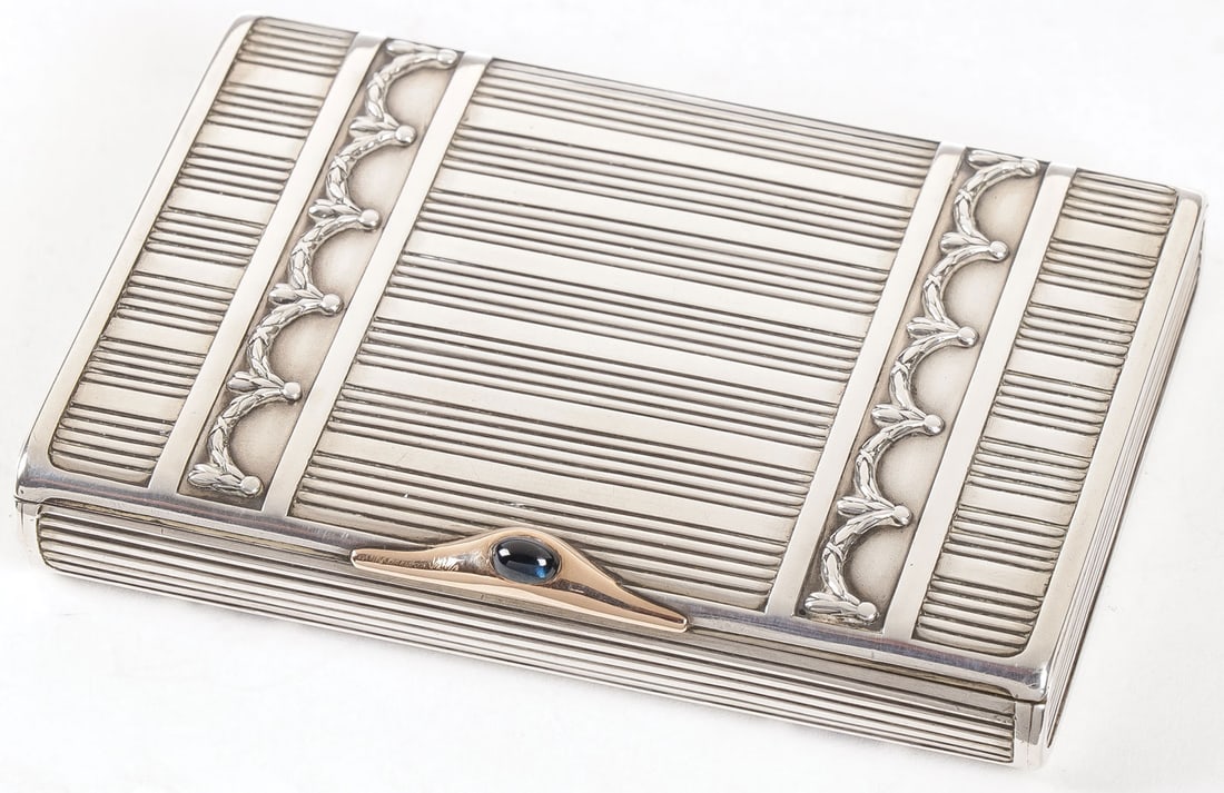A FABERGÉ SILVER CIGARETTE CASE, MOSCOW 1899: A FABERGÉ SILVER CIGARETTE CASE, MOSCOW 1899-1908. The body reeded and banded with garland swags. The hinged lid with gold mounted blue cabochon thumbpiece, and the interior brightly gilded. Hall