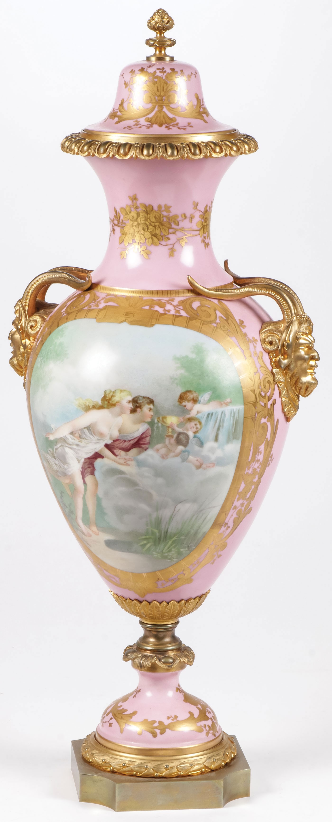 FRENCH ORMOLU MOUNTED PORCELAIN LIDDED URN: FRENCH ORMOLU MOUNTED PORCELAIN LIDDED URN. Comprising a large and impressive Sèvres style lidded hand painted porcelain urn, with gilt bronze laurel ring base, gilt bronze horned head masks on shoul