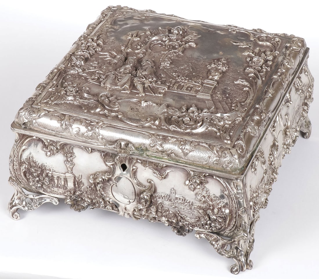 LARGE CONTINENTAL SILVERED DRESSER BOX, 19TH C.: LARGE CONTINENTAL SILVERED DRESSER BOX, 19TH C.. Resting on four scroll feet and overall decorated in the Rococo style, the sides with vistas and the hinged lid with an ornately modeled scene of court