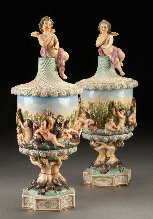 CAPODIMONTE STYLE NEOCLASSICAL LIDDED URNS: A PAIR OF CAPODIMONTE STYLE NEOCLASSICAL LIDDED URNS, EARLY 20TH CENTURY, POSSIBLY RICHARD KLEMM, DRESDEN. Each with putto and dolphins in deep relief raised on figural mermaid bases and surmounted by