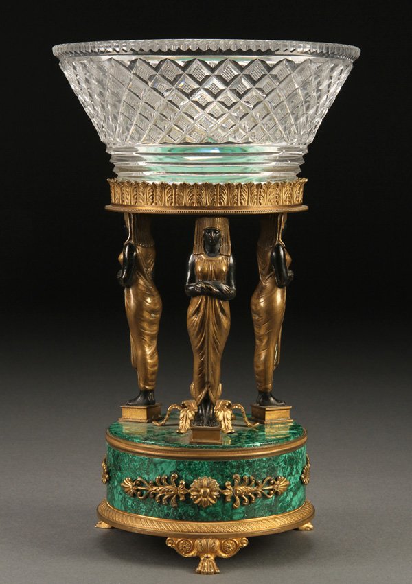 FRENCH MALACHITE & GILT BRONZE STAND: A FRENCH EMPIRE MALACHITE AND GILT-BRONZE STAND, 19TH CENTURY. With three standing Egyptian female figures above a circular malachite base with gilt bronze feet supporting a diamond cut glass flared c