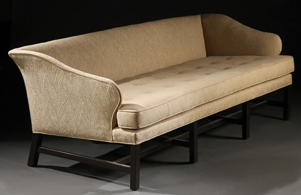 SOFA, EDWARD WORMLEY FOR DUNBAR: EDWARD WORMLEY FOR DUNBAR, SOFA, MID 20TH CENTURY. With tufted cushion below gently scrolled armrests. Upholstered in cream tapestry fabric and on dark- stained legs.