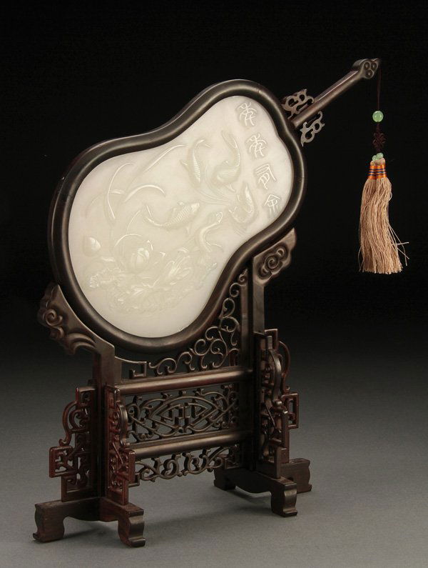 A CHINESE CARVED WHITE JADE TABLE SCREEN: A FINE CHINESE CARVED WHITE JADE AND HARDWOOD TABLE SCREEN. The translucent even-toned white jade plaque carved in relief with four fish, aquatic plants and four character inscription. Mounted in a f