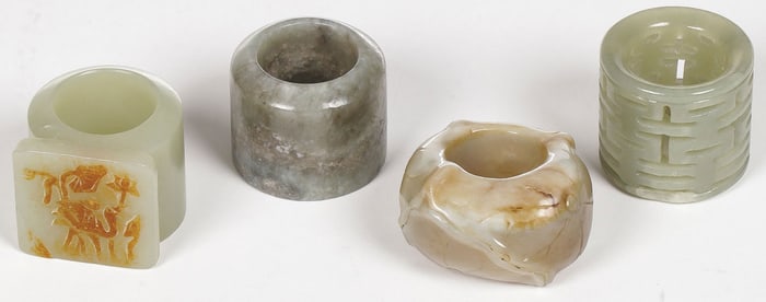 FOUR CHINESE CARVED JADE ARCHER RINGS