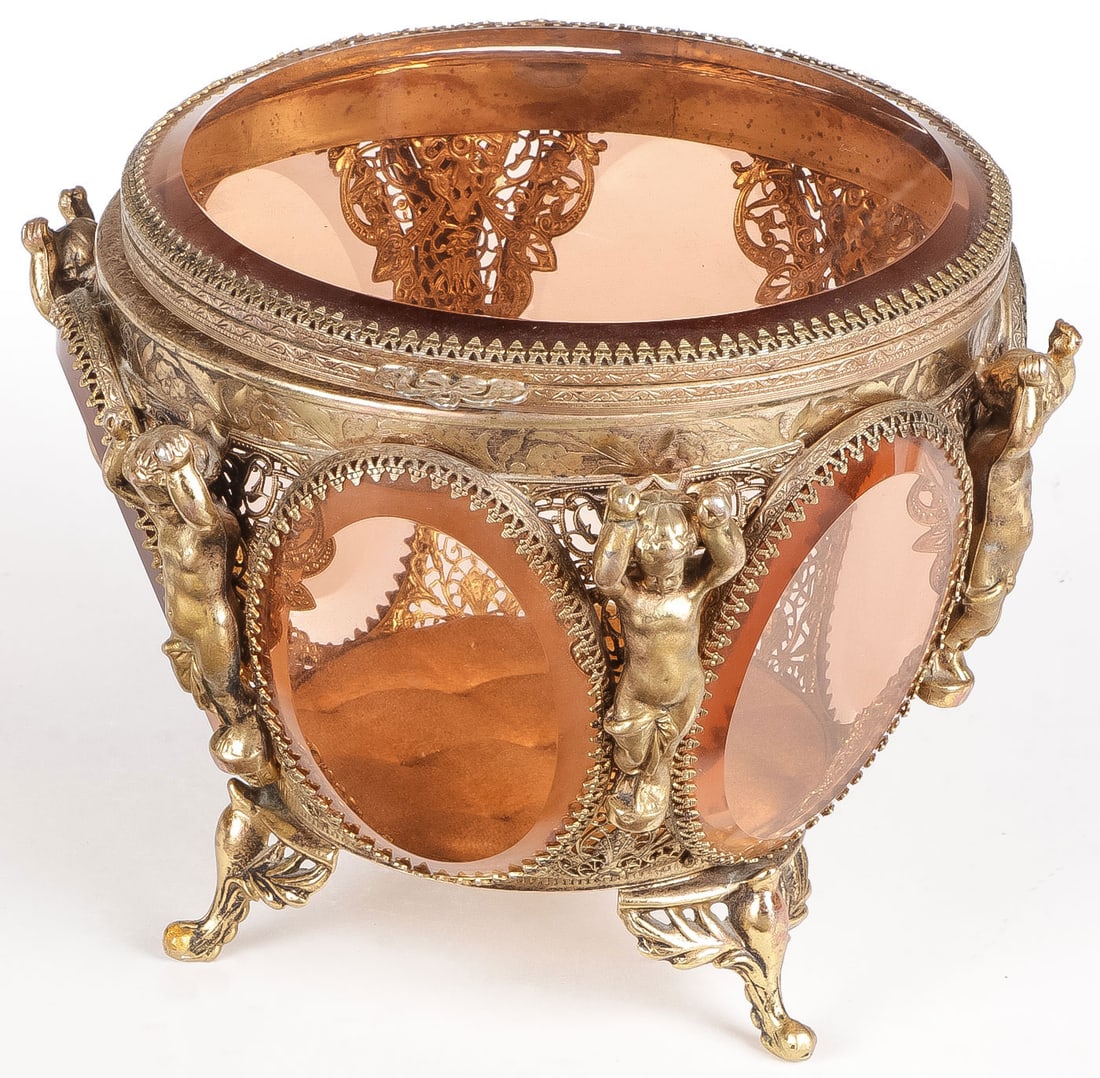 IMPRESSIVE GILT BRONZE MOUNTED GLASS CASKET: IMPRESSIVE GILT BRONZE MOUNTED GLASS CASKET. Comprising a complex gilt mounted casket the sides composed of six oval beveled glass panels divided by six putti beneath a circular beveled glass hinged l