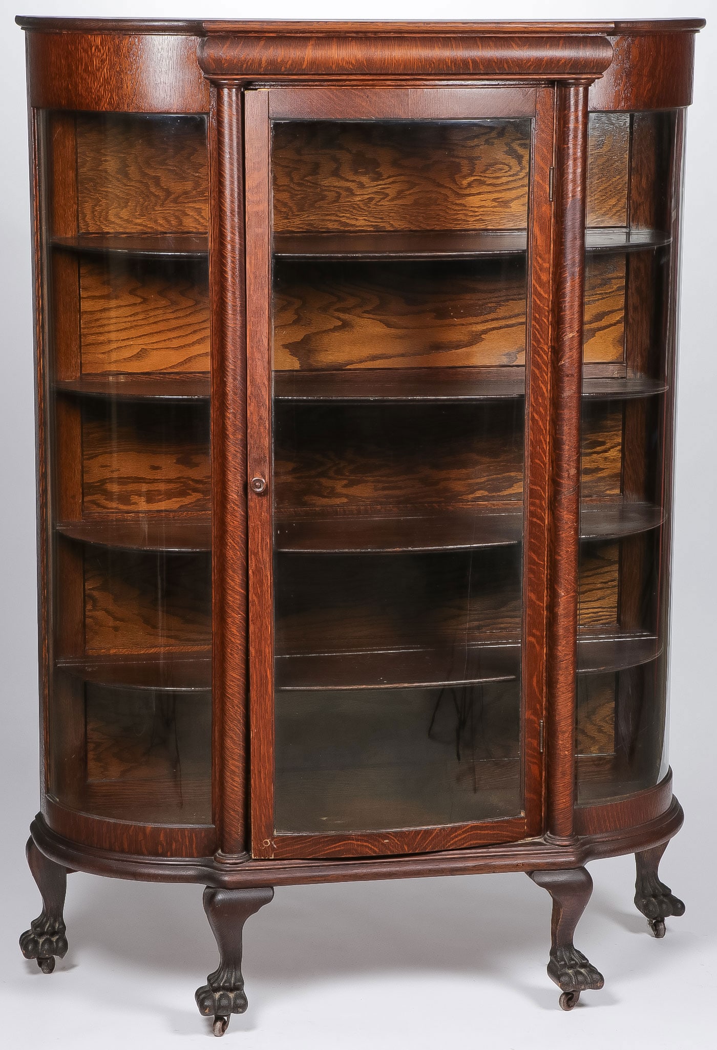 AMERICAN OAK CURVED GLASS CHINA CABINET: AMERICAN OAK CURVED GLASS CHINA CABINET. Of traditional design, with four fitted shelves and on Queen Anne legs terminating in claw feet. Height 67 inches, width 46 inches, depth 15.25 inches. NO RESE