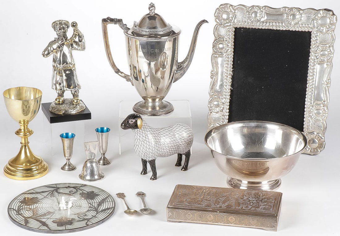 DECORATIVE METAL ARTS GROUP: DECORATIVE METAL ARTS GROUP. Comprising 13 individual pieces including a silver frame, a silver-gilt Jewish man blowing a rams horn, a gilt and sterling chalice, a silver overlay glass trivet, pair of