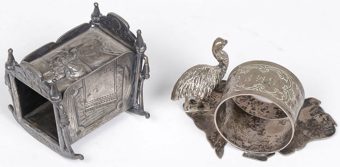 RARE SILVER-PLATED NAPKIN HOLDER: RARE SILVER-PLATED NAPKIN HOLDER. Comprising two silver plated napkin rings including a scarce James W. Tufts Baby in Cradle napkin ring together with an ostrich English silver plated napkin ring. Gre