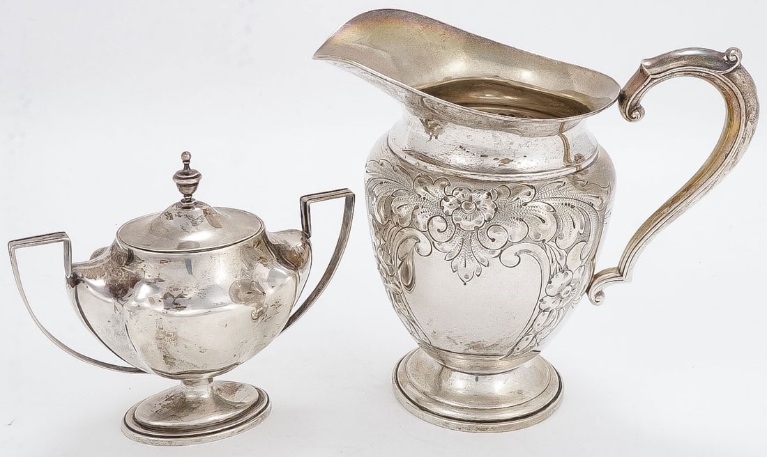 STERLING SILVER PITCHER & CREAMER: STERLING SILVER PITCHER & CREAMER. Comprising a large, chased Frank M. Whiting water pitcher and a non-matching sterling silver covered sugar. Greatest height 9.25 inches (23.5cm). Total weight 1,000 