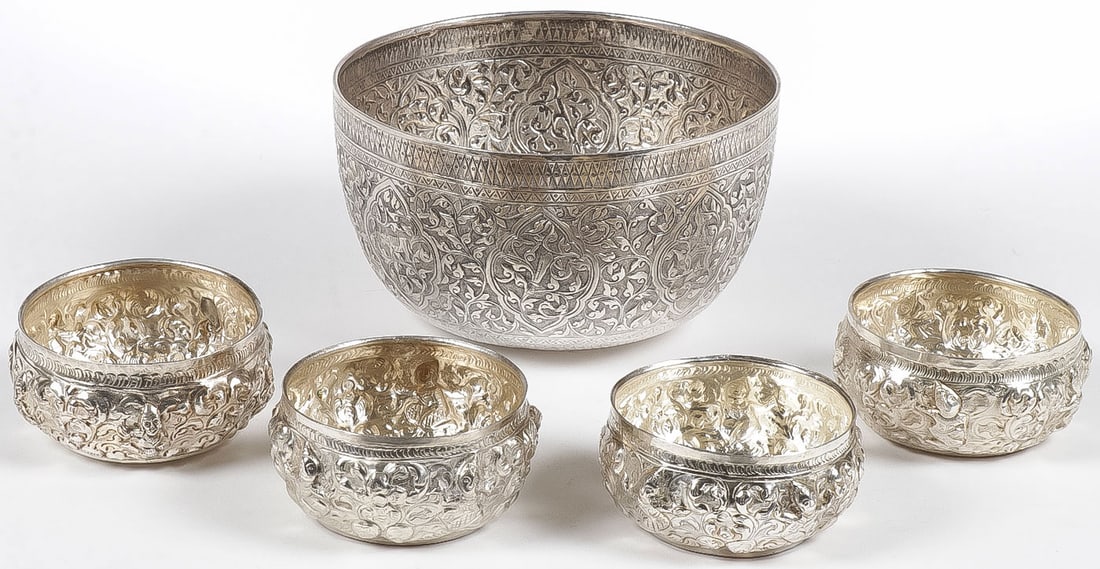 VINTAGE BURMESE OFFERING BOWLS: VINTAGE BURMESE OFFERING BOWLS. Comprising one large example and four matching smaller examples each heavily repoussed with traditional motifs. Each unmarked, presumably silver plated. Greatest height