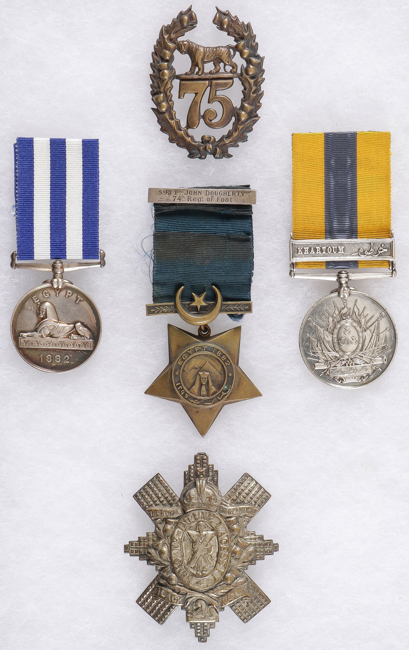 BRITISH EGYPT SERVICE MEDALS & BADGES, 19TH C: BRITISH EGYPT SERVICE MEDALS & BADGES, 19TH C. Comprising 5 individual pieces including a 75th (Stirlingshire) Regiment of Foot cap badge, The Egypt Medal, the rim engraved, W. Bawes. ORD: H.M.S."IRLs