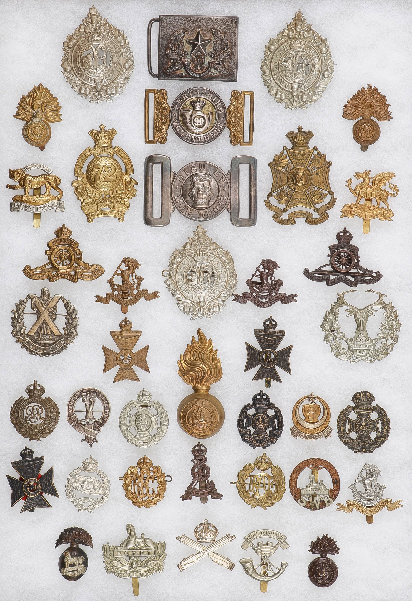 GOOD GROUP OF 39 BRITISH HAT BADGES & BUCKLES: GOOD GROUP OF 39 BRITISH HAT BADGES & BUCKLES. Comprising 39 individual cap badges and belt buckles circa 1880-1920. Including three Argyll and Sutherland Highlanders cap badges, a silver Cameronians 