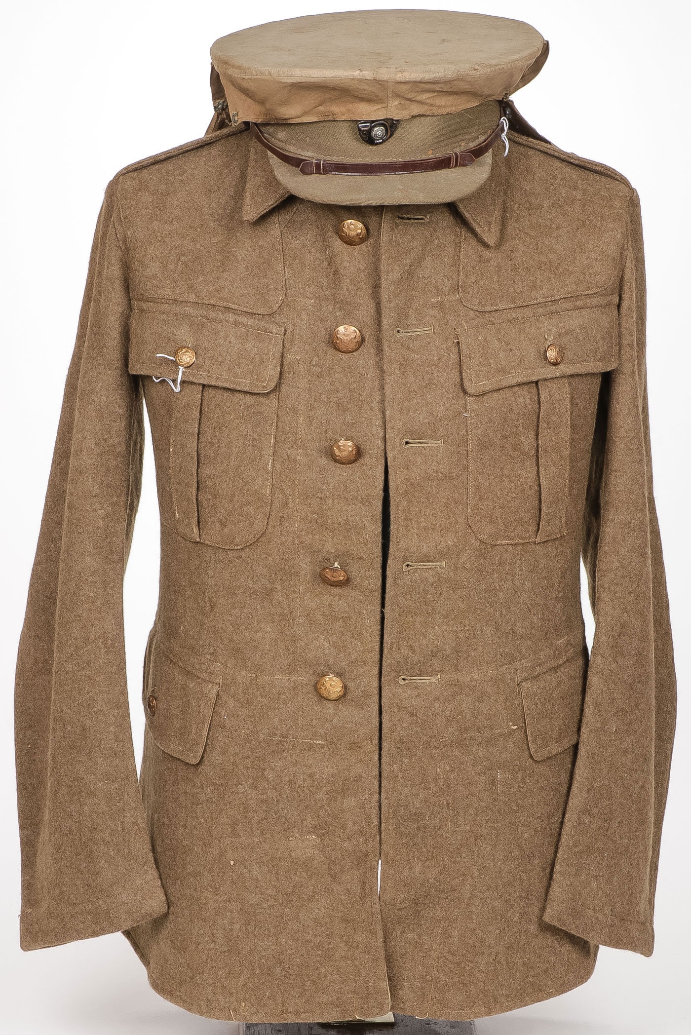 BRITISH WWI TUNIC AND VISOR CAP: BRITISH WWI TUNIC AND VISOR CAP. Comprising a four-pocket wool blouse dated 1917, together with a visor cap with a scarce rain cover. Overall approximately 30 x 19 inches.
