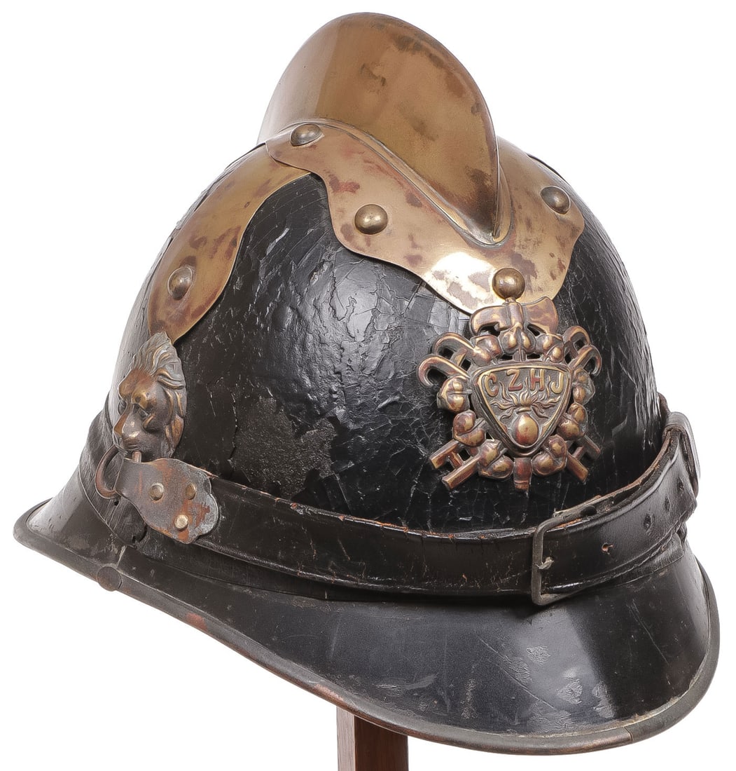 A CEZCH FIREFIGHTERS HELMET C. 1920: A CEZCH FIREFIGHTERS HELMET C. 1920. The leather body with gilt brass riveted crest, lions head bosses with leather chin strap and the front with the badge of the CZHJ (the Czech Provincial Fire Briga