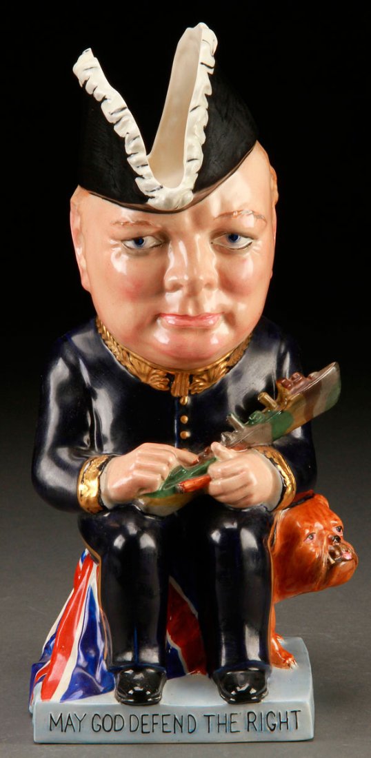 A CLARICE CLIFF SEATED WINSTON CHURCHILL JUG: A CLARICE CLIFF FOR WILKINSON SEATED WINSTON CHURCHILL JUG, CIRCA 1941. Modeled holding a ship in his lap and seated on a Union Jack with bulldog. Embossed "And may God defend the right". Royal Staffo