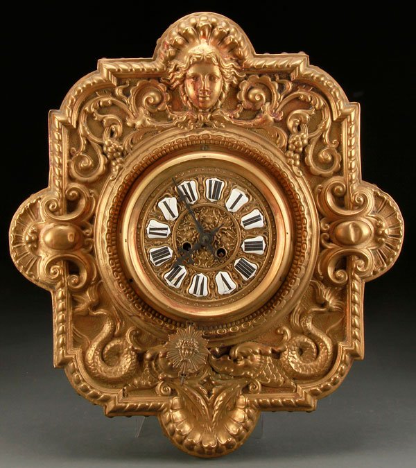 GERMAN BLACK FOREST RENAISSANCE STYLE BRASS CLOCK: A GERMAN BLACK FOREST RENAISSANCE STYLE BRASS WALL CLOCK, LATE 19TH CENTURY. With rococo scrolled decoration, facial mask and dolphins surrounding a circular clock movement. Height 20.5 inches (52 cm)