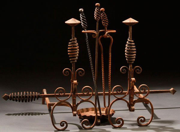 A PAIR OF ARTS AND CRAFTS WROUGHT IRON ANDIRONS: A PAIR OF ARTS AND CRAFTS WROUGHT IRON ANDIRONS, CIRCA 1900. With open coiled decoration. Comprising two andirons, with an associated two piece tool set with holder. Height of andiron 26 inches (67 cm