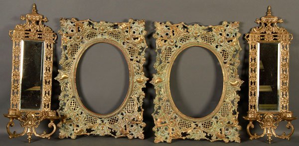A SIX PIECE BRASS DECORATIVE ARTS GROUP: A SIX PIECE BRASS DECORATIVE ARTS GROUP, 20TH CENTURY. Comprising two Renaissance style reticulated bronze oval picture frames, two mirrored bronze candle wall sconces, and two Louis XVI style bronze 