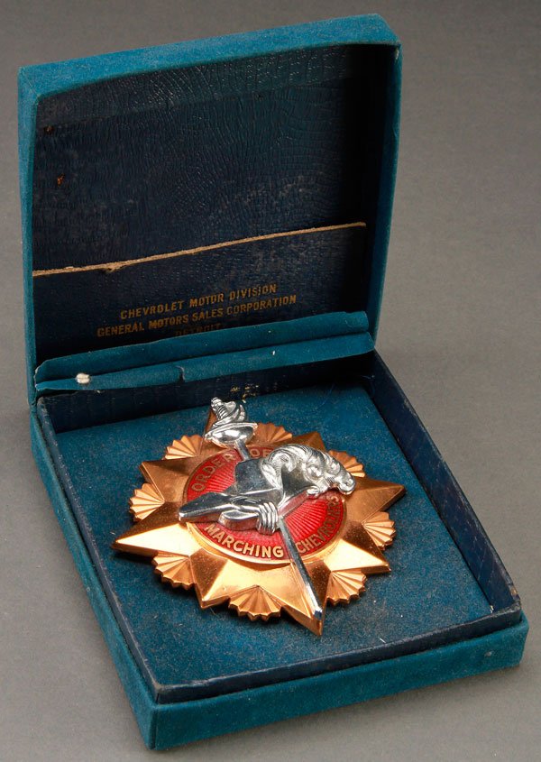 CHEVROLET ORDER OF MARCHING CHEVROLIERS BADGE: A RARE CHEVROLET "ORDER OF MARCHING CHEVROLIERS" ENAMELED BRONZE GRILL BADGE, CIRCA 1930S. Contained in the original box. Apparently a General Motors sale corporation salesman award. Diameter 4.75 inc