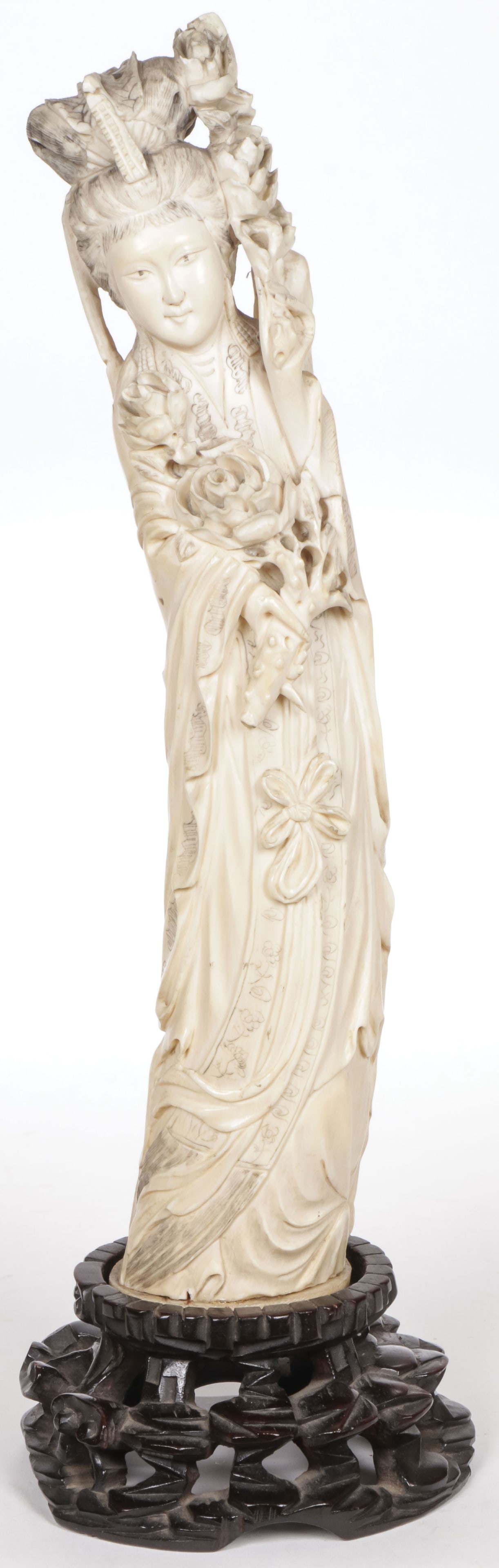 CHINESE CARVED MAIDEN, QING: CHINESE CARVED MAIDEN, QING. Finely carved in full round, with deep folds, pierced-carved flower blossoms, and tinted etched hair, resting on a conforming carved wood stand. Overall height including s