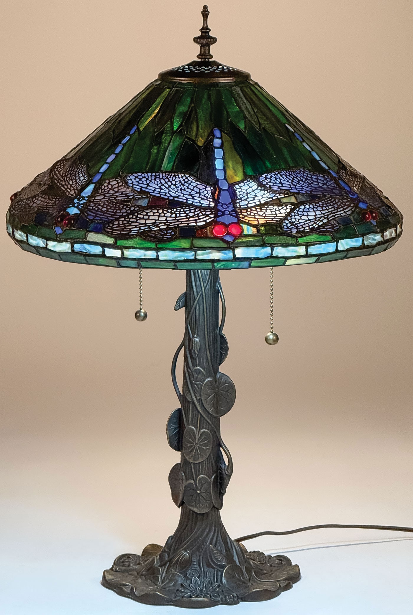 TIFFANY STYLE LEADED GLASS DRAGONFLY LAMP: TIFFANY STYLE LEADED GLASS DRAGONFLY LAMP. With vined covered tree trunk base and leaded shade with cabochon jewels. Height 24.5 inches. Modern.SHIPPING NOTICE:If you are not using the Live Auctione