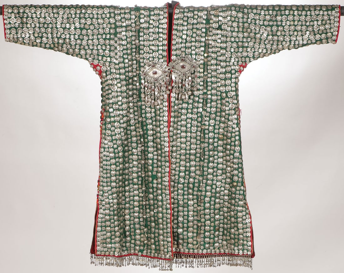 ATTRACTIVE TURKMEN DOWRY COAT: ATTRACTIVE TURKMEN DOWRY COAT. Comprising an ornate and heavily decorated Turkmen dowry coat, 20th century. The green wool body entirely covered with embossed white metal discs and platelets, large di