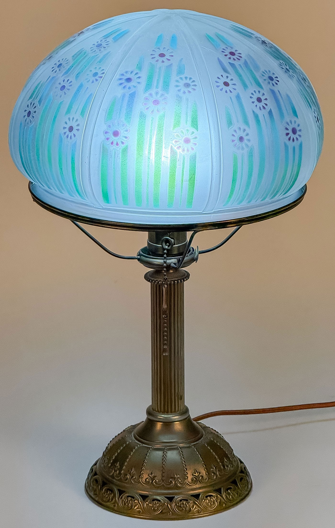 BRADLEY & HUBBARD TABLE LAMP: BRADLEY & HUBBARD TABLE LAMP. With pierced brass domed base and fluted column, supporting a domed stencil-floral-decorated one-piece glass shade (rim chip), underside of base with circular B. & H. me