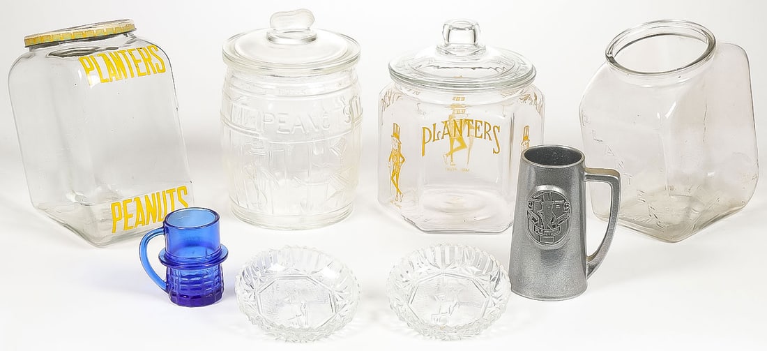 PLANTER'S PEANUT JARS AND RELATED ITEMS: PLANTER'S PEANUT JARS AND RELATED ITEMS. Comprising four glass Planters Peanuts counter jars, one missing lid; two glass Mr. Peanut trays; a blue glass Mr. Peanut handled cup; and a pewter Planters P