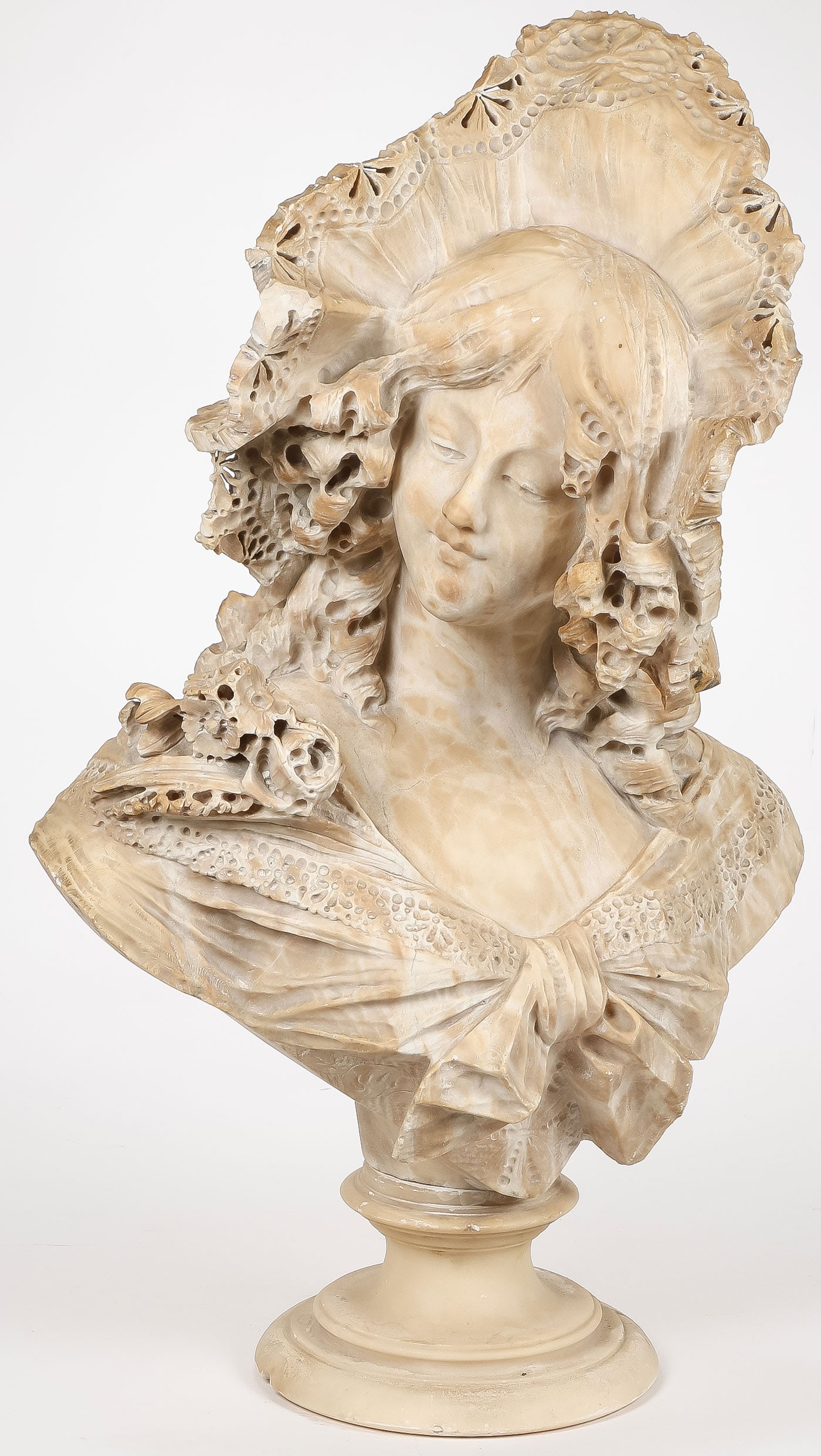 LARGE CARVED SPANISH BEAUTY, C. 1890: LARGE CARVED SPANISH BEAUTY, C. 1890. Comprising a large and ornately carved marble or alabaster bust of a young beauty with a lace hat and cascading curls, resting on a socle base. Unsigned. Height 2