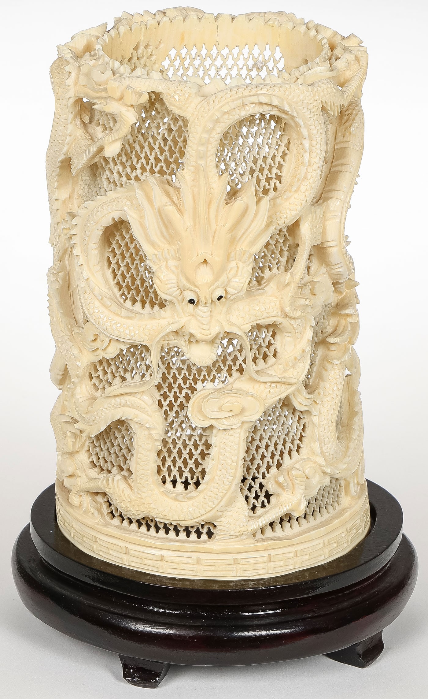 CHINESE PIERCED CARVED DRAGON VASE, C. 1900: CHINESE PIERCED CARVED DRAGON VASE, C. 1900. Comprising a finely carved lattice-work vase, overall decorated with dragons and resting on a conforming wood base. Height 7.5 inches (19 cm). NO INTERNATI