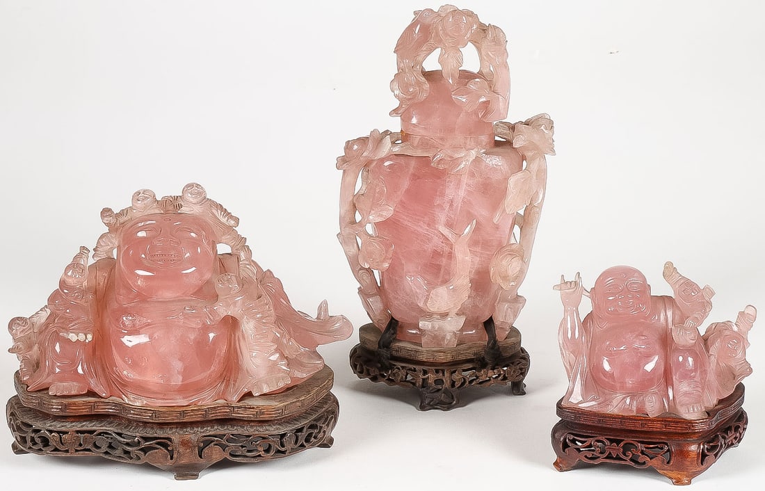 3 PCS CHINESE CARVED PINK QUARTZ: 3 PCS CHINESE CARVED PINK QUARTZ. Comprising two finely carved, seated, laughing Buddhas, each on conforming pierced-carved wood stands, and a lidded vase with blossoming branches. Greatest height 10