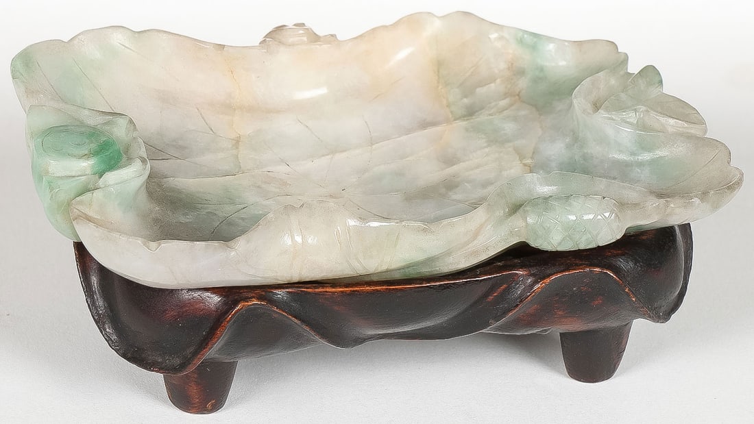 CHINESE CARVED JADE BRUSH WASHER, QING: CHINESE CARVED JADE BRUSH WASHER, QING. Comprising a carved jade lotus-form brush washer, carved on both sides and resting on a conforming wood stand. Length 4 inches (10cm).SHIPPING NOTICE:If you a