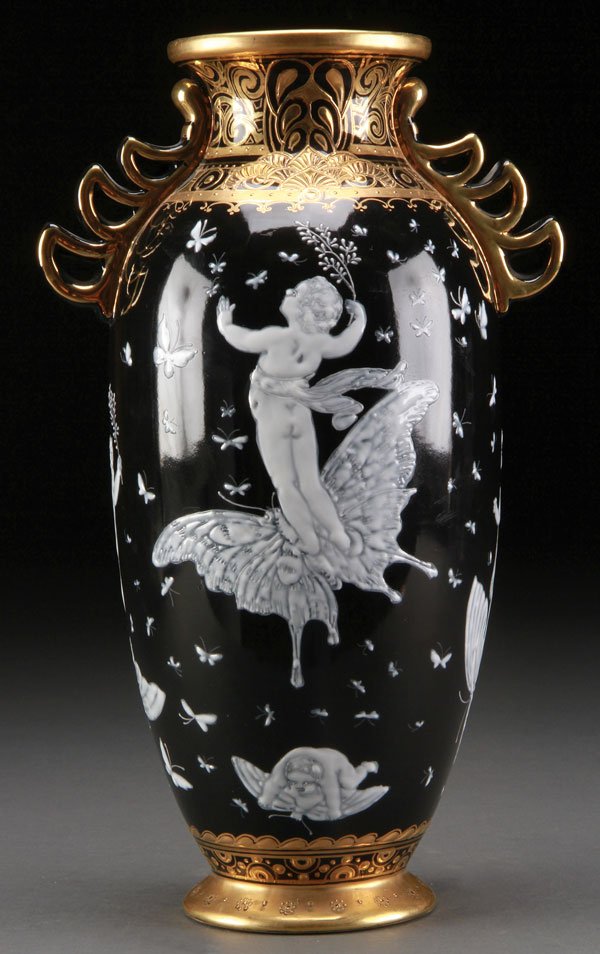 PATE-SUR-PATE STYLE & GILT DECORATED VASE: A PATE-SUR-PATE STYLE AND GILT DECORATED BLACK GROUND HANDLED VASE, 20TH CENTURY. In the manner of Minton. With an Art Nouveau scene depicting putti riding atop butterflies. Unmarked. Height 13 inches