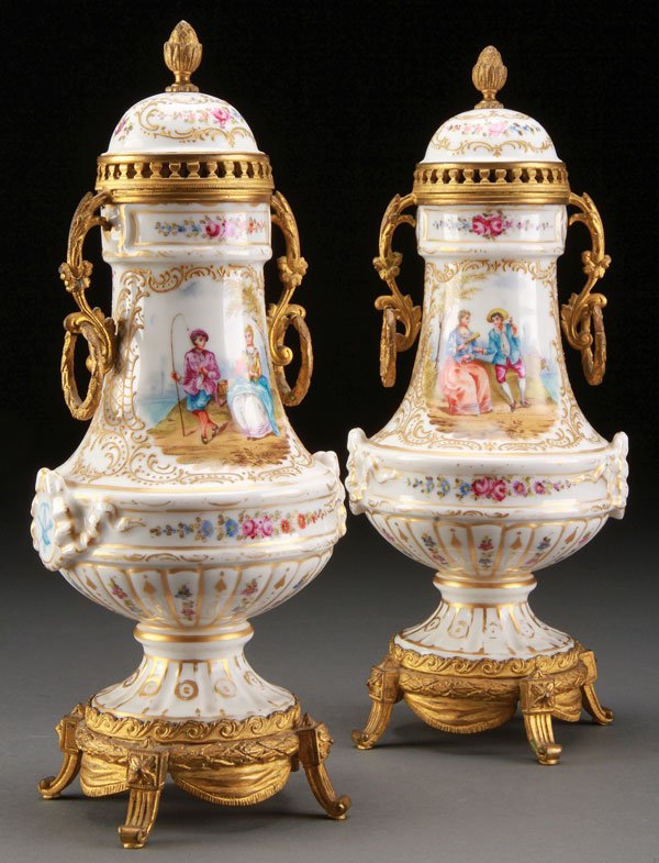 TWO DRESDEN PORCELAIN & GILT BRONZE MOUNTED URNS: A PAIR OF DRESDEN PORCELAIN AND GILT BRONZE MOUNTED LIDDED URNS, LATE 19TH CENTURY. Each decorated with romantic pastoral scenes and floral sprays, raised on a gilt bronze four footed stand. The porce