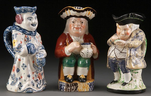 TWO STAFFORDSHIRE PEARLWARE TOBY JUGS, 19TH C: TWO STAFFORDSHIRE PEARLWARE TOBY JUGS, 19TH CENTURY. Depicting a seated man with pitcher and a standing snuff taker (repairs). Together with a Delft woman with pitcher, base inscribed "B.P." in blue g