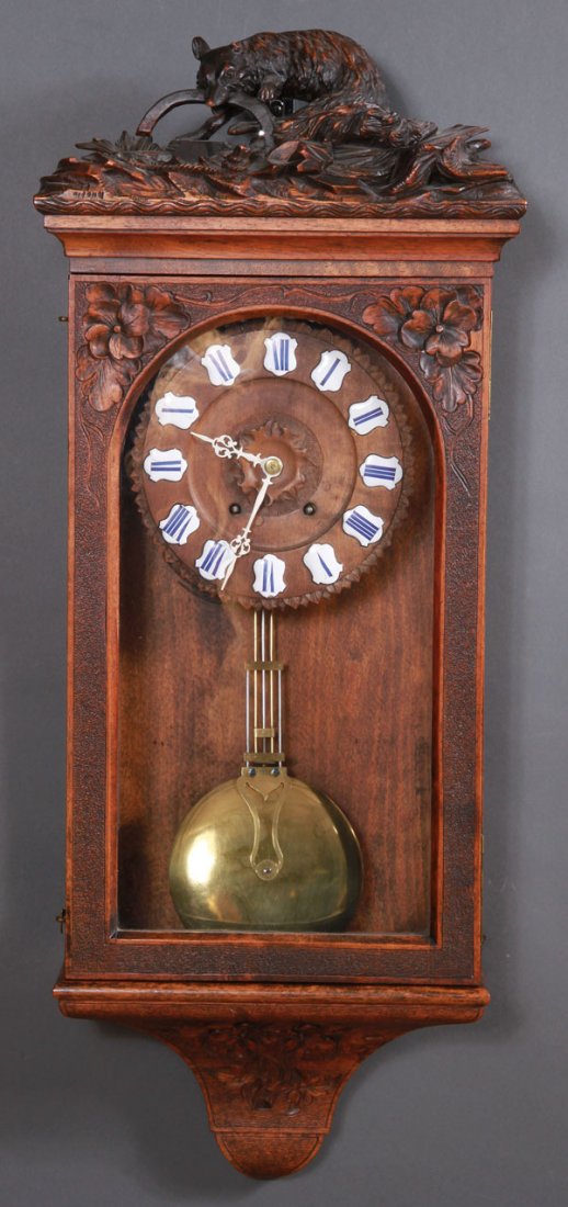 SWISS CARVED "BLACK FOREST" REGULATOR CLOCK: AN INTERESTING SWISS CARVED "BLACK FOREST" HUNT SCENE REGULATOR CLOCK, LATE 19TH CENTURY. The walnut case surmounted with a carved figural fox in trap, containing a carved walnut clock dial with ename