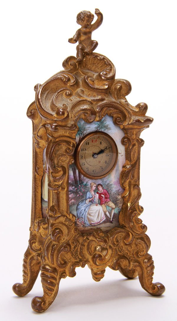 VIENNESE AND GILT BRONZE ENAMELED DRESSER CLOCK: A VERY FINE VIENNESE AND GILT BRONZE ENAMELED DRESSER CLOCK, LATE 19TH CENTURY. Finely enameled with romantic courting scenes within a gilt bronze Rococo clock case surmounted with a putto. Height 5 i