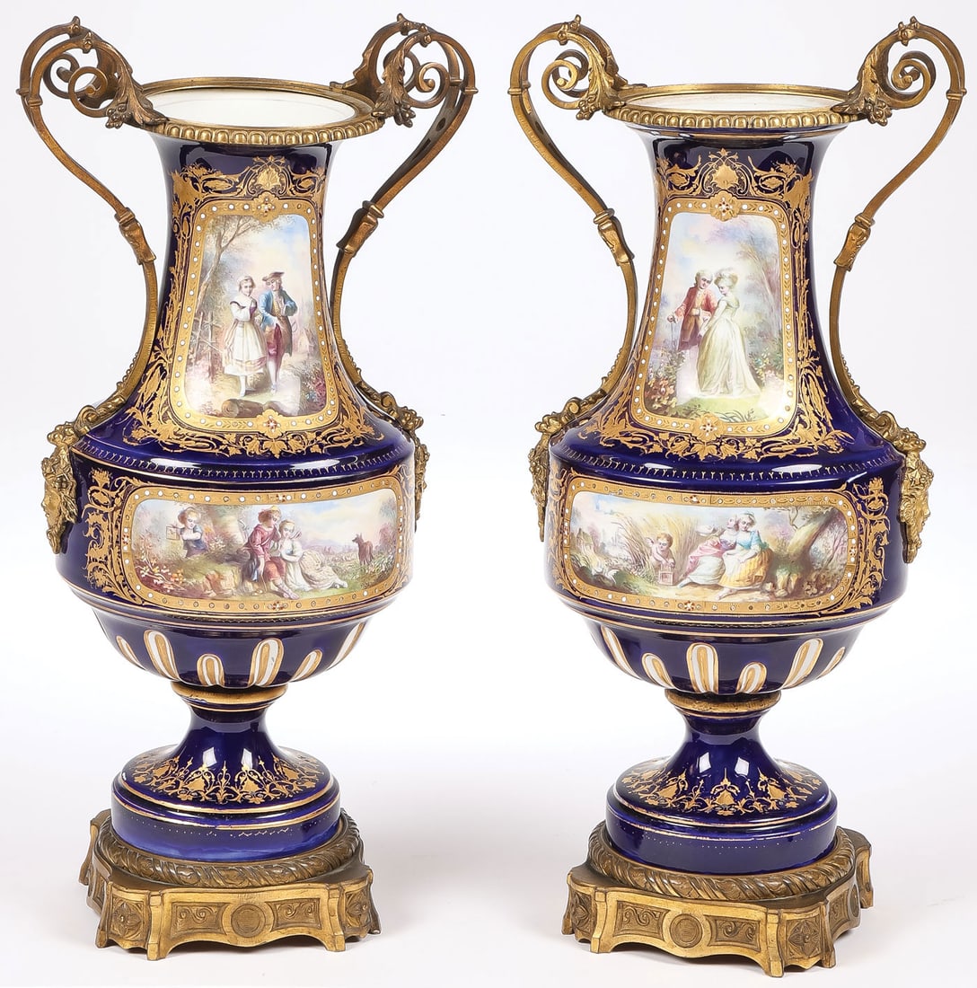 PR HAND PAINTED SEVRES URNS: PR HAND PAINTED SEVRES URNS. Comprising a pair of hand painted, gilt decorated cobalt urns, Sevres or Sevres style, circa 1880. Resting on gilt bronze bases, the shoulders with ornate gilt scroll