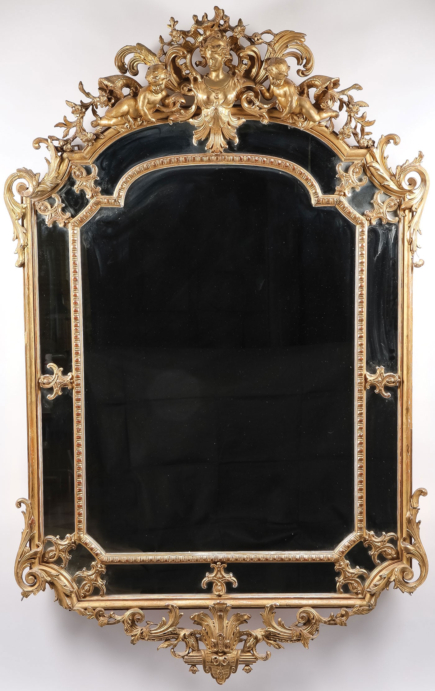 19TH C. CARVED & GILT WOOD WALL MIRROR: 19TH C. CARVED & GILT WOOD WALL MIRROR. Comprising an ornate Rococo style carved gilt wood wall mirror, 19th century. The crest featuring the bust of a maiden flanked by putti and surrounded by