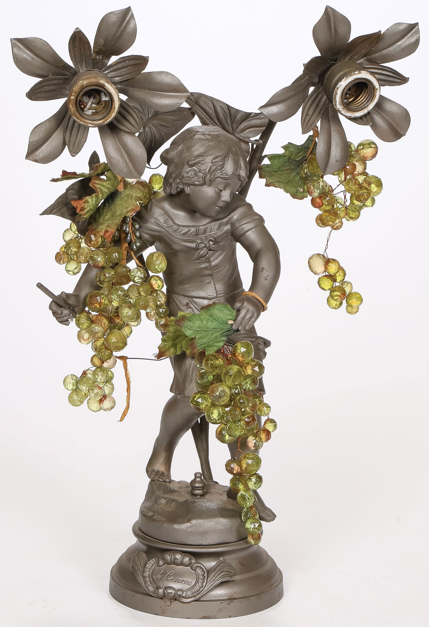 FRENCH FIGURAL LAMP: FRENCH FIGURAL LAMP. Comprising a charming figure of a young child with two light sockets of flowering form and overlaid with cut glass grapes. Signed on base Aug. Moreau. Height 21 inches (51cm). SHI