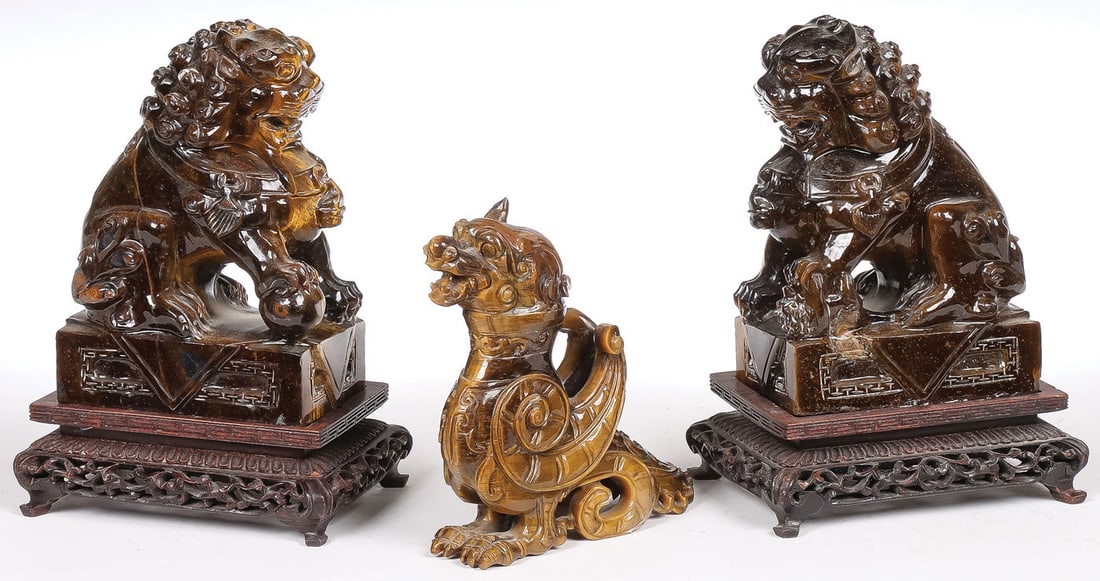 CHINESE CARVED TIGERS EYE: CHINESE CARVED TIGERS EYE. Comprising a pair of finely carved tiger's eye foo lions resting on matching pierced carved conforming wood stands, together with a finely carved seated lion eagle (tip of