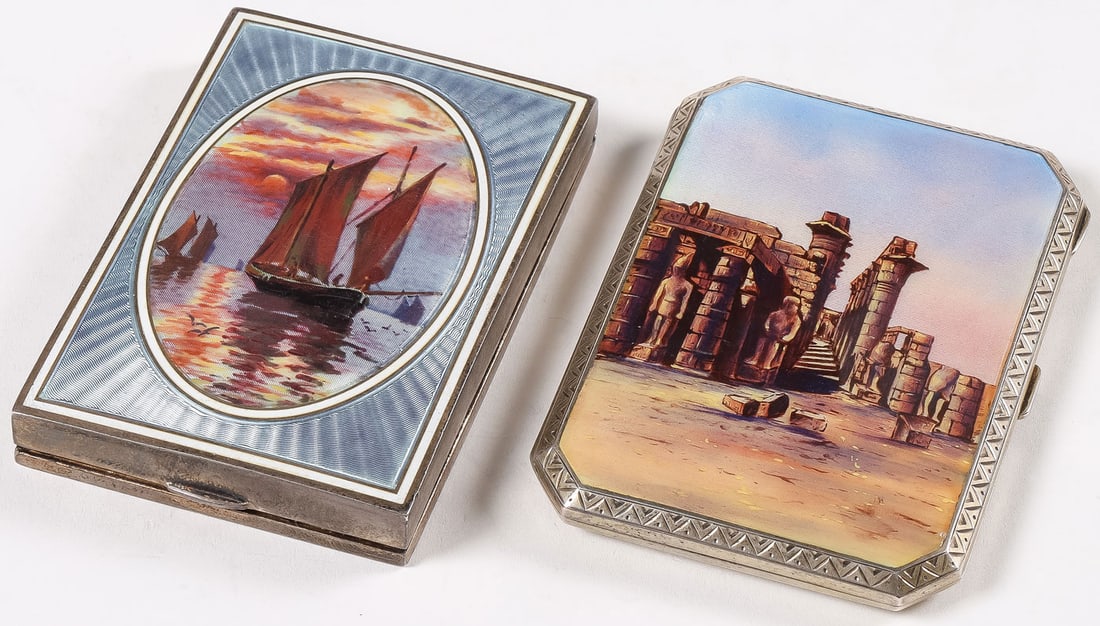 2 SILVER AND ENAMEL VANITY CASES: 2 SILVER AND ENAMEL VANITY CASES. Comprising a rectangular case with squared corners, the hinged lid with enamel-painted Egyptian ruins and with chased borders, the back of case overall engraved with 