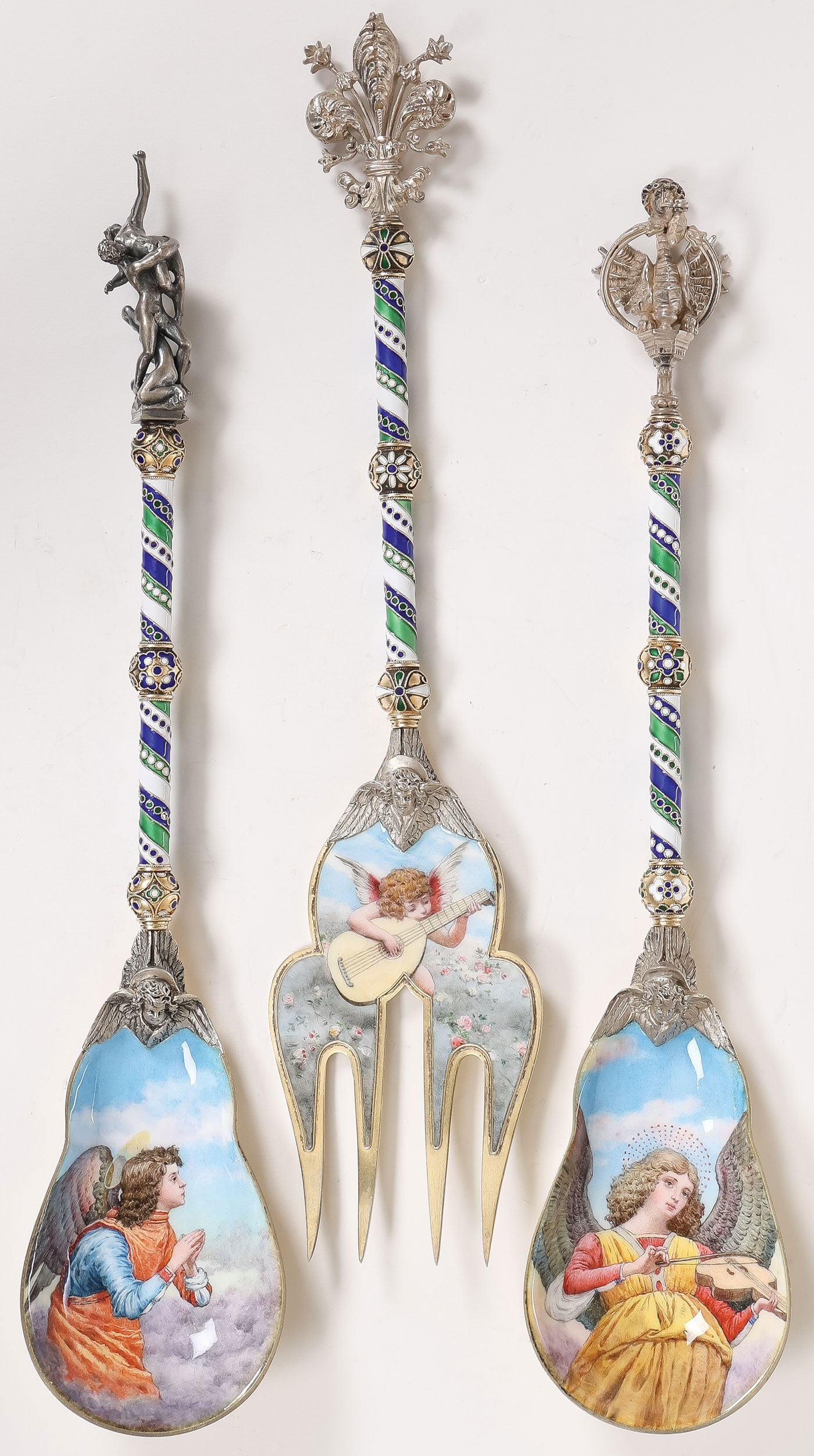 3 EXCEPTIONAL ENAMELED SERVING UTENSILS, C. 1890: 3 EXCEPTIONAL ENAMELED SERVING UTENSILS, C. 1890. Comprising two large silvered, gilded, and enameled serving spoons and a fork, likely Italian or Austrian, circa 1890. The bowl of one spoon with enam