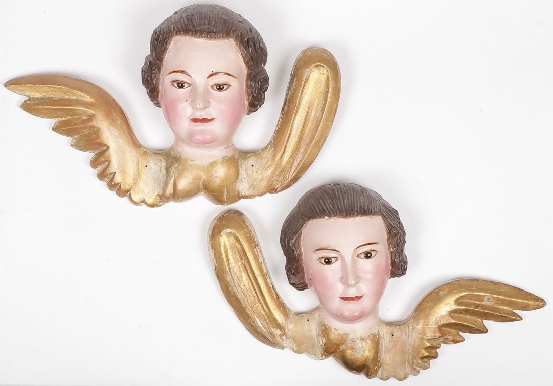 CARVED WINGED CHERUB HEADS, 18TH C: CARVED WINGED CHERUB HEADS, 18TH C. Comprising a pair of opposing carved, polychrome, and gilt-wood winged cherub heads, Continental, 18th century, flat-backed and the heads set with glass eyes. Each