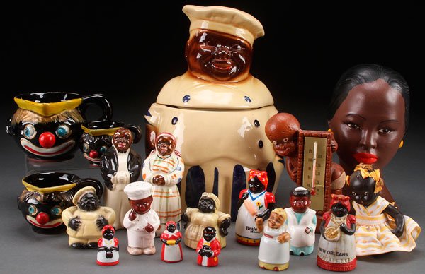 A 19 PIECE BLACK AMERICANA DECORATIVE TABLEWARES: A 19 PIECE BLACK AMERICANA DECORATIVE TABLEWARES GROUP. Comprising a chef cookie jar (crack), various types of salt and pepper shakers, a jointed bisque doll, figural measuring cups, novelty thimbles,