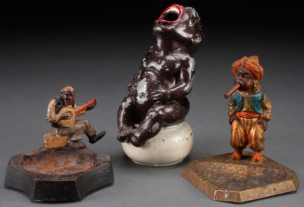 THREE BLACK AMERICANA FIGURAL ASH TRAYS NOVELTY: THREE BLACK AMERICANA FIGURAL ASH TRAYS. Comprising a black boy on pot, a cigar smoking bobble head or nodder, and an uncle Tom figural cast iron ash tray. Largest height 6.25 inches (16 cm).