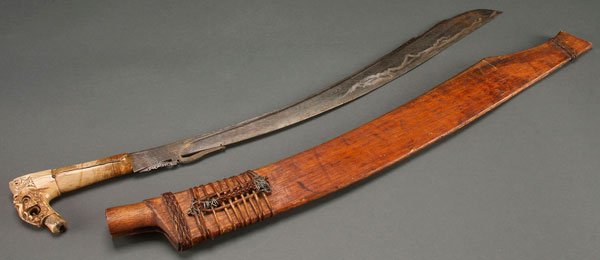 AN INDONESIAN KRIS (SWORD), WITH CARVED BONE HANDLE: AN INDONESIAN KRIS (SWORD), EARLY 20TH CENTURY. With carved bone handle, brass inlaid blade, and carved mahogany sheath. Length 26.75 inches (68 cm).